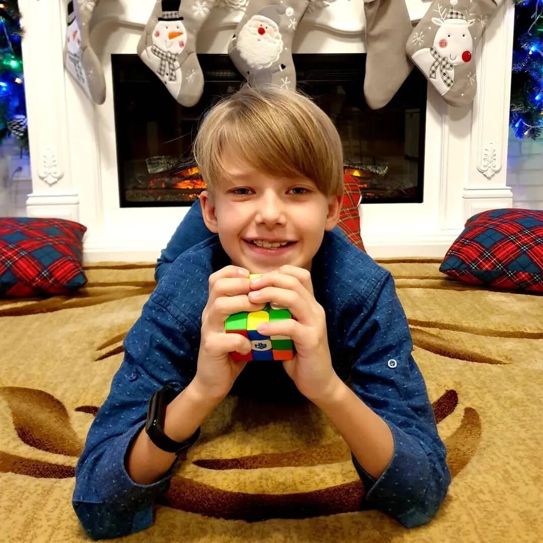 Timofei smiling and holding a 3x3 speed cube at home