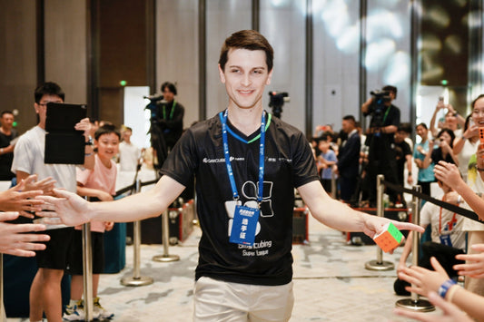 Speedcubing competitor holding a 3x3 cube, greeting fans at a competition event