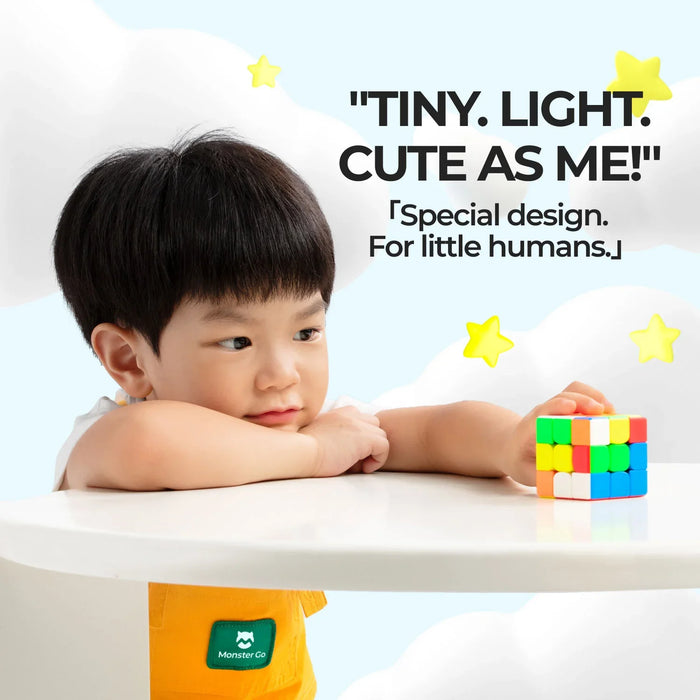 Young boy in orange Monster Go outfit playing with colorful Rubik's cube on white table