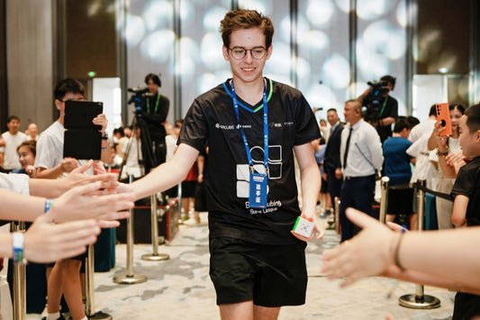 Speedcuber at competition holding 3x3 cube, greeting fans in event venue