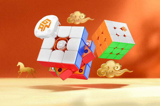 Speed cubes with orange, white, and green faces and internal mechanism, floating on festive orange background with gold clouds and a horse illustration.